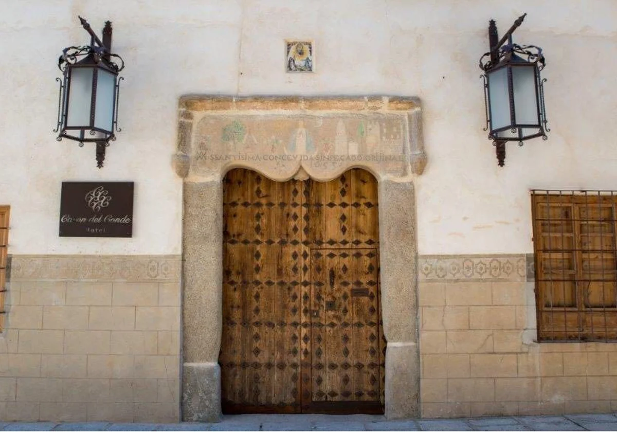 Portada de piedra del Casón del Conde en Orgaz, con el dintel tallado, los faroles de forja y la puerta de clavos