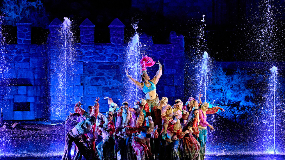 gran escenario iluminado con efectos de agua y fuego en el espectaculo nocturno el sueno de toledo en puy du fou