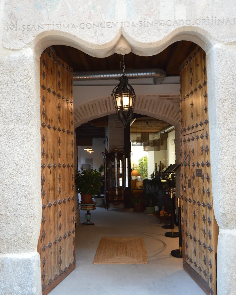Portón de madera claveteada del Casón del Conde abierto, con el patio al fondo