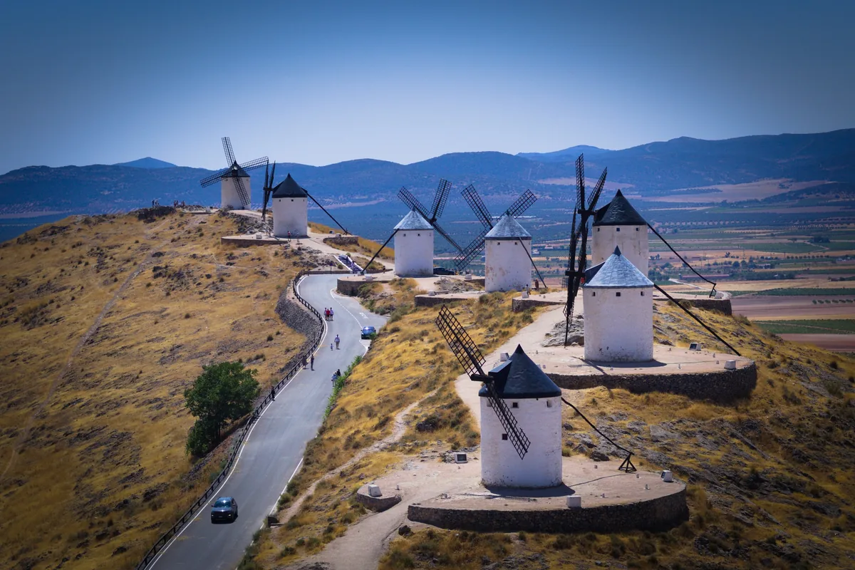 Carretera que sube entre los molinos del Cerro Calderico de Consuegra, con coches y gente a pie