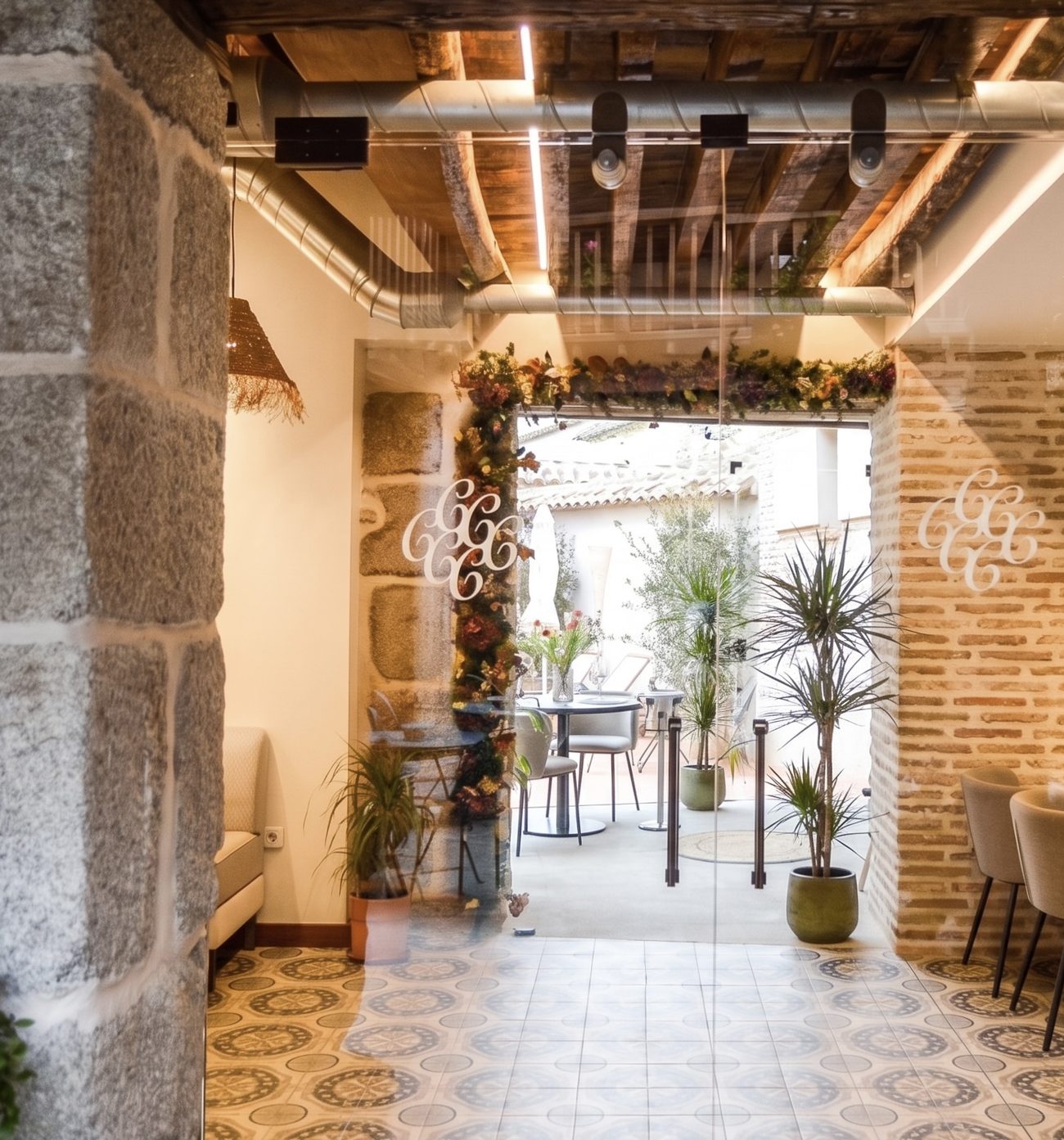 El comedor de La Condesa se abre a la terraza a través de las puertas de cristal, con el suelo de baldosa hidráulica y el patio al fondo