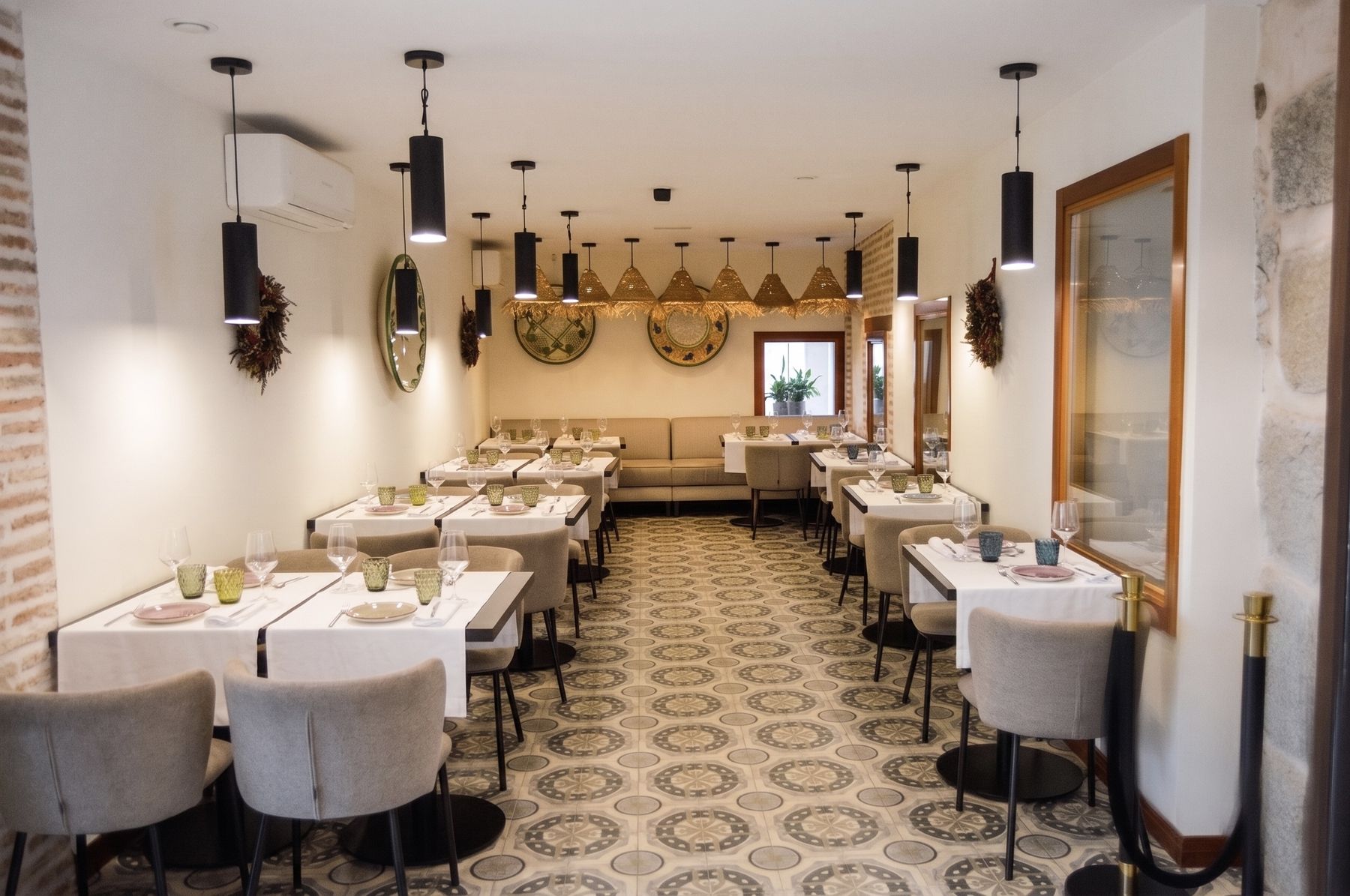 Sala del restaurante La Condesa con las mesas puestas, la cerámica manchega en la pared y el suelo de baldosa hidráulica