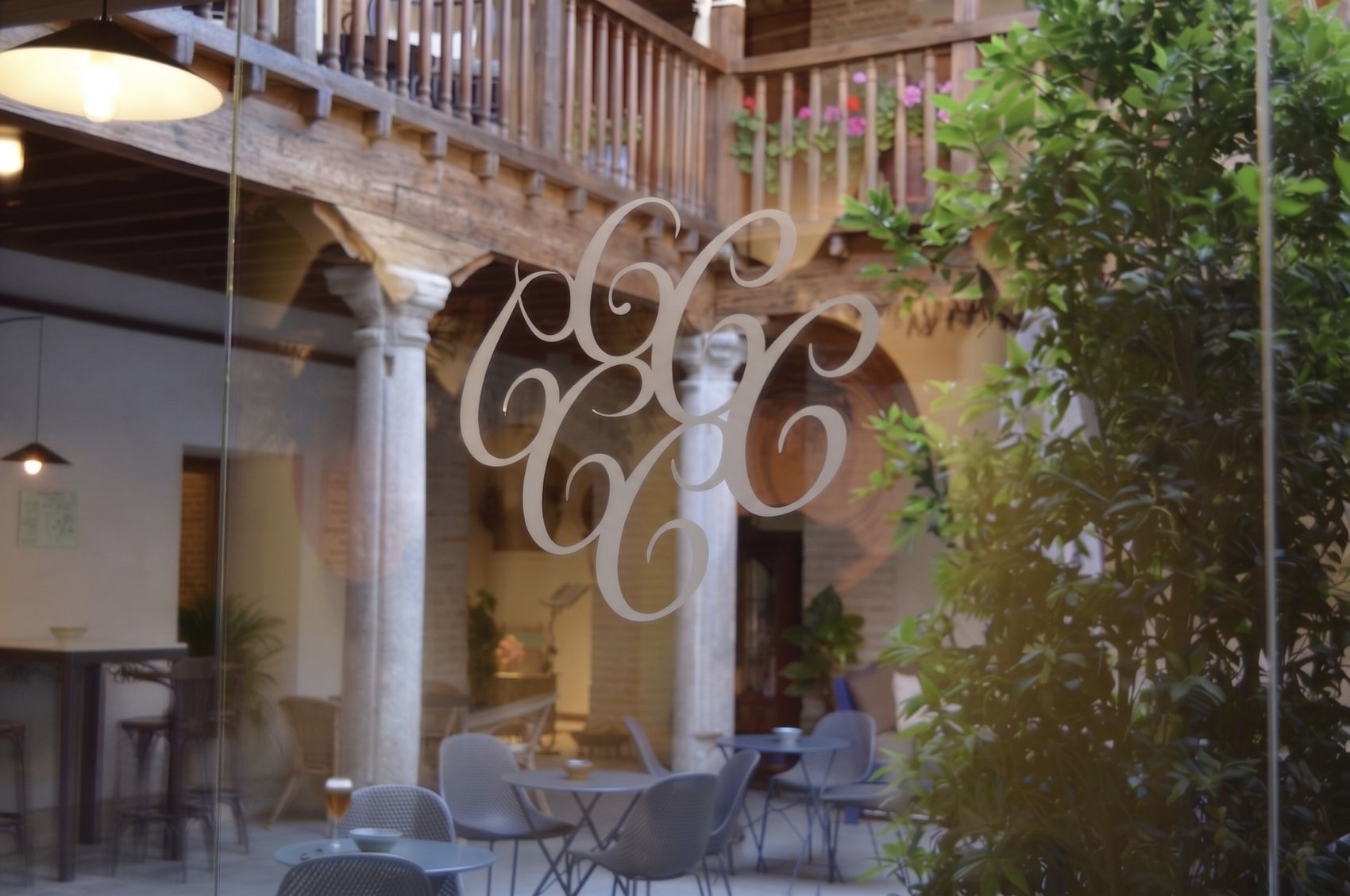 Monograma grabado en el cristal, con el patio de columnas del Casón del Conde al fondo